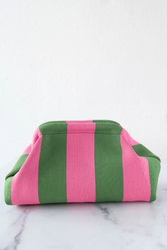 a pink and green striped purse sitting on top of a marble counter next to a white wall