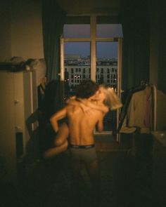 a man and woman are dancing in front of a window with the city skyline outside