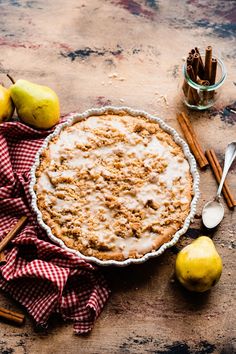 a pie sitting on top of a table next to apples and cinnamon sticks