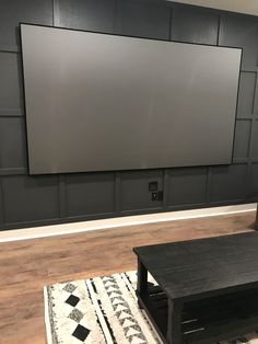 a flat screen tv mounted to the side of a wall in a living room next to a coffee table