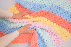 someone is crocheting a multicolored blanket