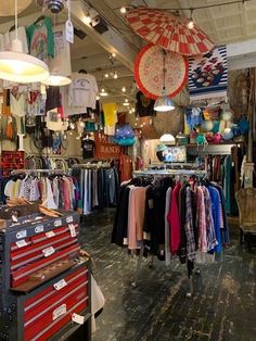 the inside of a clothing store with umbrellas hanging from the ceiling and clothes on display