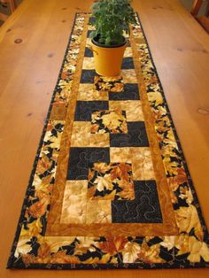 a potted plant sitting on top of a wooden table next to a black and yellow runner