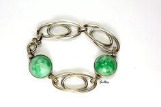 "This beautiful bracelet has green faux Jade / Peking glass. There are 2 glass cabochon and 3 silver tone metal links, and a spring clasp. It is almostb7\" long and the weight of it is 0.9 oz. If you want to take advantage of the reduced shipping you must contact me before you pay for your items so I can send you a corrected invoice. Thank You for visiting our Etsy store https://www.etsy.com/shop/VictoryIssweet !" Green Metal Bracelets For Formal Occasions, Formal Green Metal Bracelets, Retro Green Bracelet Jewelry, Green Cabochon Metal Jewelry, Retro Green Oval Jewelry, Green Metal Cabochon Jewelry, Adjustable Vintage Jade Bracelets, Vintage Green Bracelet With Patina, Silver Bohemian Jade Bracelets