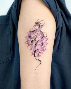 a woman's arm with a tattoo on it that has a dragon and flowers