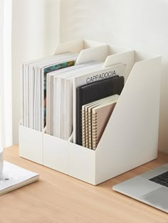 a laptop computer sitting on top of a wooden desk next to a white book holder