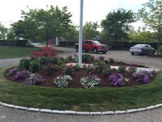 a flower bed in the middle of a driveway with cars parked on the other side