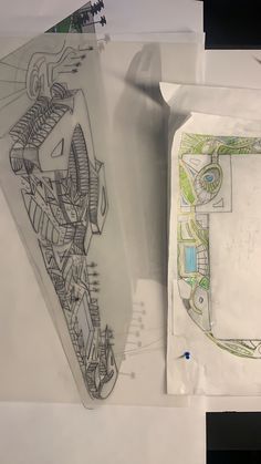 some drawings are laying on top of paper and one has a drawing of a building