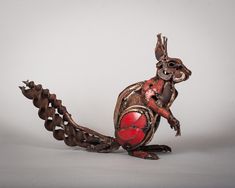 an animal made out of metal with red paint on it's body and tail