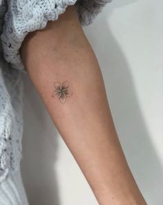 a woman's arm with a small spider tattoo on the left side of her arm