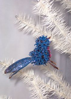 a blue ornament hanging from a white christmas tree