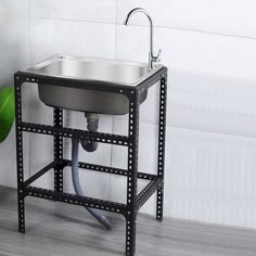 a stainless steel sink and faucet in the corner of a room with white tile walls