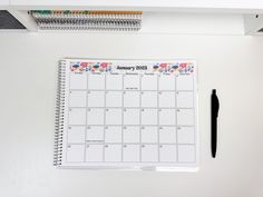 a white desk with a calendar and pen on it