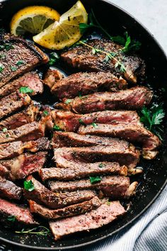 steaks and lemon slices in a skillet with parsley on the side, ready to be cooked