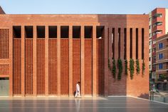 a person standing in front of a red brick building with vertical slats on it