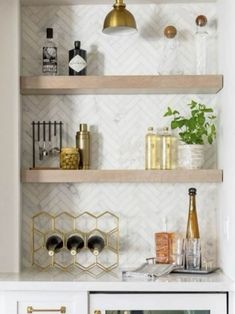 the shelves in this kitchen are decorated with gold and white accessories, such as wine bottles