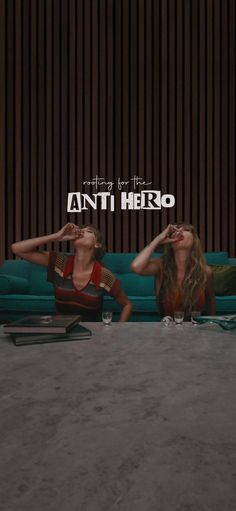 two women sitting on the floor in front of a blue couch with an anti hero logo above them