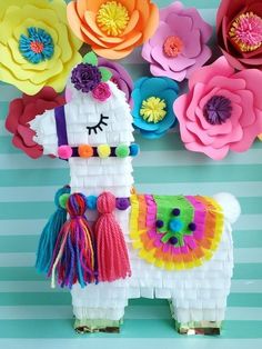 a llama made out of construction paper surrounded by colorful flowers and other decorative items