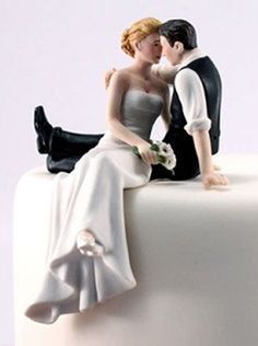 a bride and groom figurine sitting on top of a cake