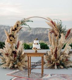 a wedding cake sitting on top of a wooden table next to tall pamodia