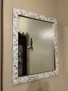 a bathroom mirror sitting on top of a wall next to a toilet paper dispenser