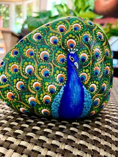 a peacock painted rock sitting on top of a table