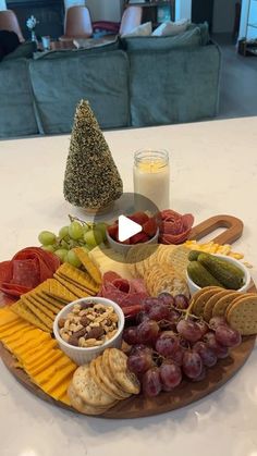 a platter with cheese, crackers, grapes, nuts and other foods on it