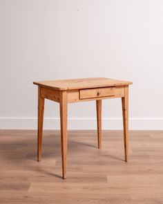 a small wooden table sitting on top of a hard wood floor next to a white wall