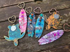 five different colored surfboards are sitting on a wooden bench with hearts hanging from them