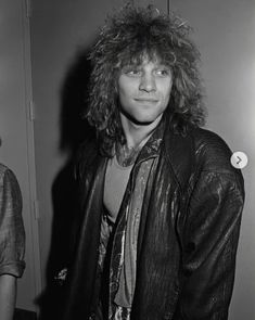 a black and white photo of a man with long hair in a leather jacket smiling