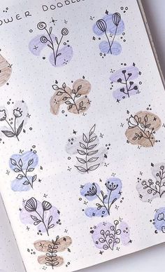 an open notebook with flowers and plants drawn on the pages, sitting on top of a table