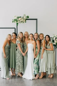 a group of women standing next to each other in front of a wall with flowers