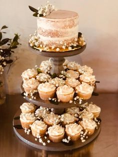 three tiered cake and cupcake display with flowers on each tier in the center