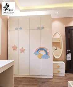 a child's bedroom with white cupboards and rainbow decorations on the doors, along with an oval mirror