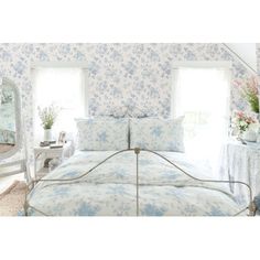 a bedroom with blue and white floral wallpaper, bedding and mirror in the corner