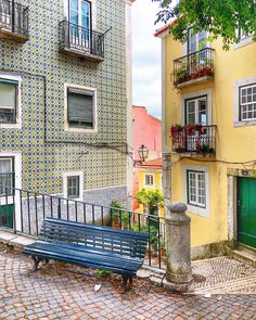 a blue bench sitting in the middle of a cobblestone street next to tall buildings