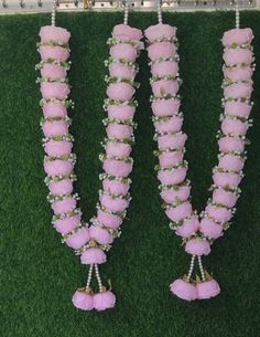 three pink flowers are attached to the side of a grass wall with beads and pearls