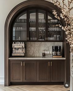 an arched doorway leads into a kitchen with marble counter tops and wooden cabinetry, along with glass front cabinets