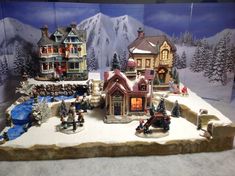 a christmas village with houses and people in the snow on display at a toy store