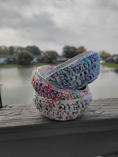 three baskets sitting on top of a wooden table next to a body of water with houses in the background