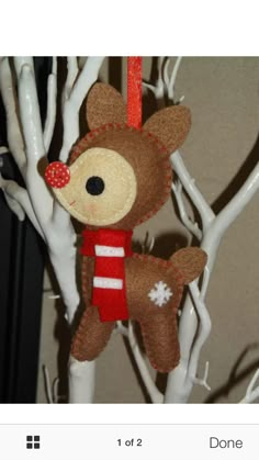 a stuffed animal hanging from a tree with white branches and red ribbon around it's neck