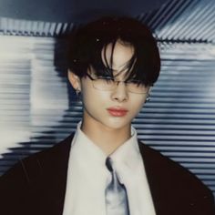 a young man wearing glasses and a tie in front of a wall with bars on it