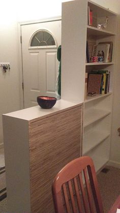 a wooden chair sitting in front of a white book shelf with a bowl on it