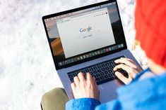 a person sitting in front of a laptop computer with the google logo on its screen