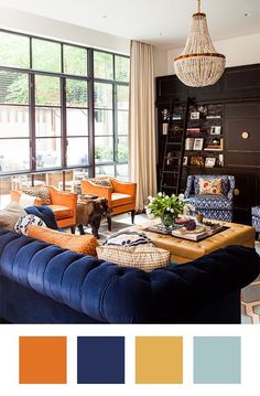 a living room with blue couches, orange chairs and a chandelier hanging from the ceiling