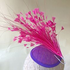 a purple hat with pink feathers on top of a mannequin's head