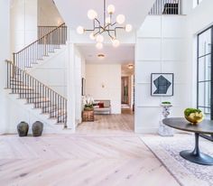 a living room filled with furniture next to a stair case and table on top of a hard wood floor