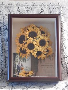 sunflowers are arranged in a vase on a lace tablecloth with an old photo