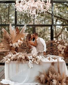 a bride and groom kissing under a chandelier