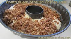 a cake in a pan with white frosting and brown sugar on top, sitting on a table